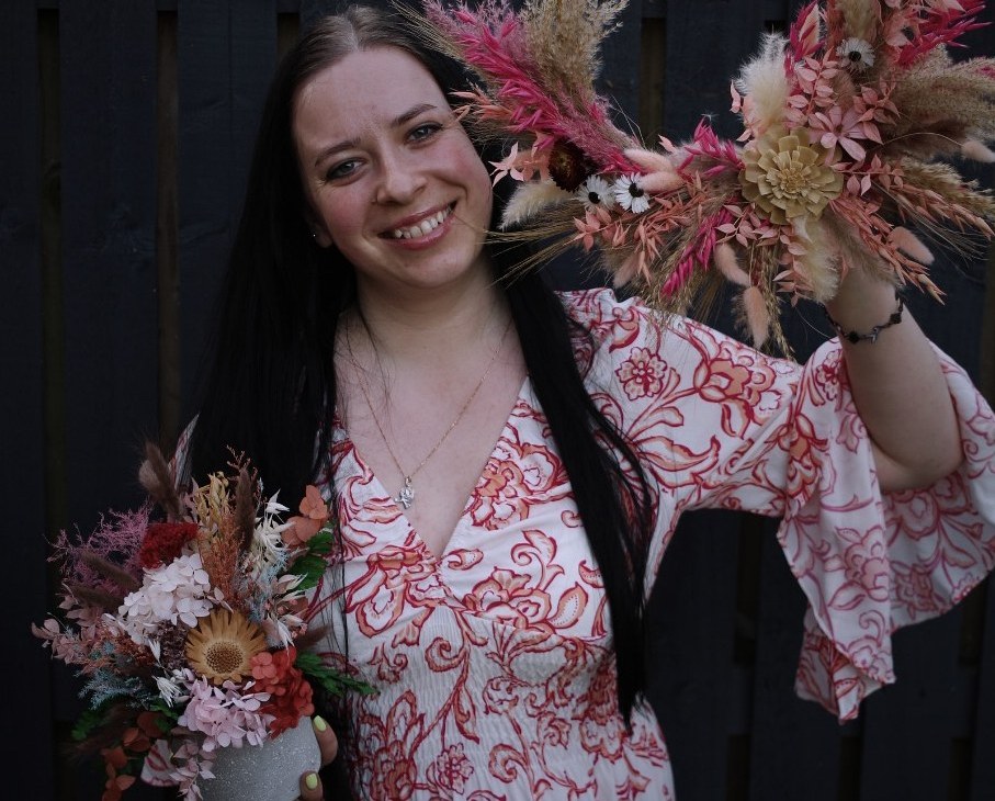 Mary, founder of Petal Ritual, holding dried flower arrangements