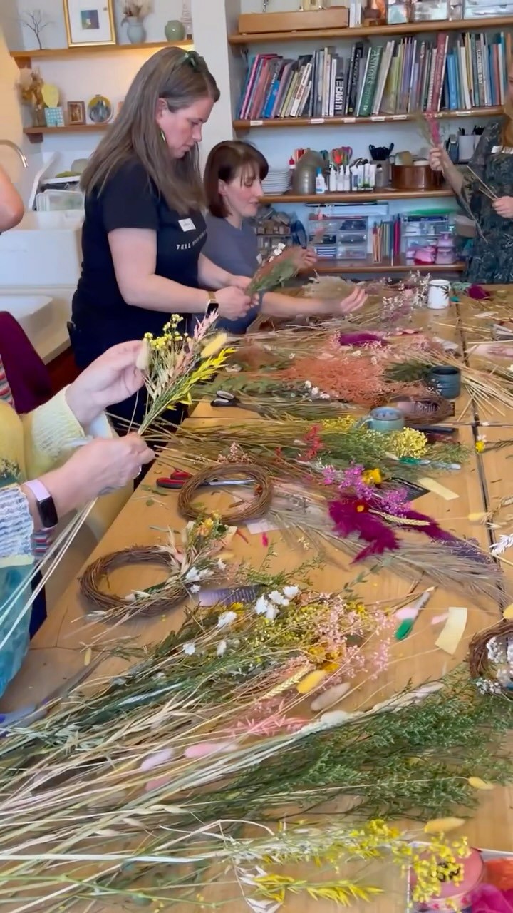 A dried flower workshop in progress, table covered in flowers and materials